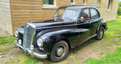 une vieille voiture noire garée devant une maison