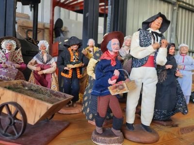 many figurines of people standing around a wheelbarrow