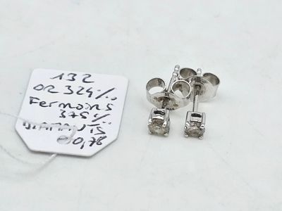 a small silver earring and a small silver earring on a white surface