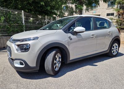 La voiture est garée sur le parking, à côté d'une clôture.