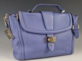 sac à main violet muni d'un cadenas sur le devant, sur fond gris