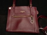 burgundy leather handbag with gold hardware and strap on a black background