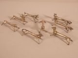 six silver dog figurines on a white surface