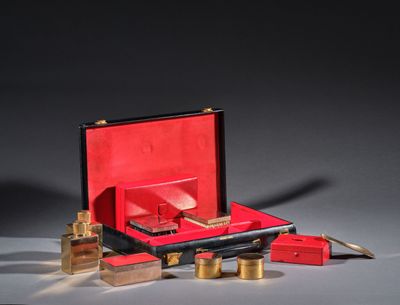 une valise rouge avec une poignée dorée et une boîte rouge avec des détails dorés