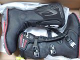 deux paires de bottes de moto dans une boîte posée par terre