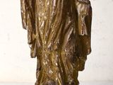 une statue représentant un homme debout sur un bloc de bois