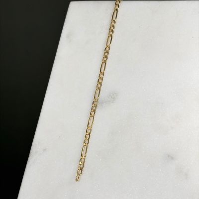 a close up of a gold chain bracelet on a marble surface
