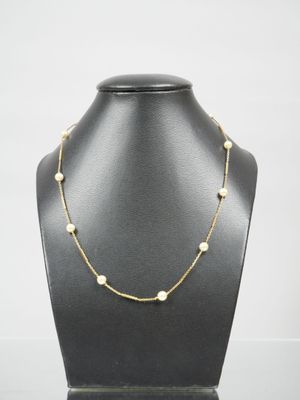 a gold necklace with pearls on a mannequin neck
