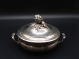 a silver plate with a bird on top of it on a black background