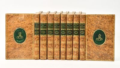 six old books are lined up in a row on a white surface