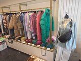 une photo d'un magasin de vêtements avec un portemanteau rempli de vêtements
