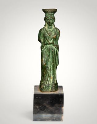a green statue of a woman with a hat on her head