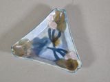 un petit objet en verre en forme de triangle orné de fleurs