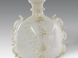 a white vase with a gold decoration on it