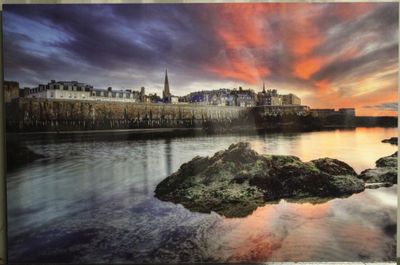 tableau représentant un coucher de soleil sur un plan d'eau, avec un château en arrière-plan