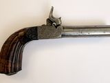 un vieux pistolet avec une crosse en bois accroché à un mur blanc