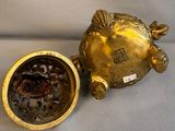 a gold vase with a turtle on it next to a gold bowl