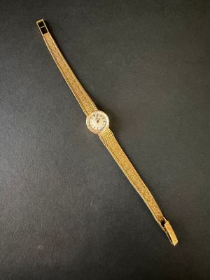 gros plan d'une montre en or sur une surface noire