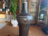 a large black vase sitting on the floor in front of a cabinet