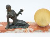 a statue of a woman sitting on a marble block next to a yellow ball