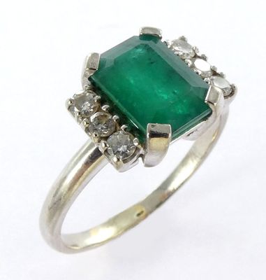 a close up of an emerald and diamond ring on a white background