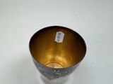 a silver cup with a tag on it sitting on a table