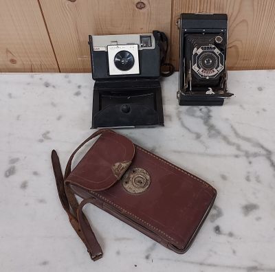 deux vieux appareils photo et un étui posés sur une table en marbre
