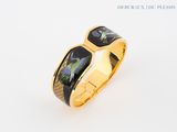 une image représentant une bague en or sur laquelle figure un oiseau noir et vert