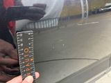 a person that is holding a ruler in front of a car