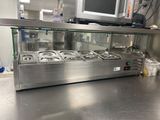 un plan de travail en acier inoxydable dans une cuisine professionnelle, avec une télévision accrochée au mur