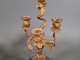 a gold colored candle holder with two candles on it