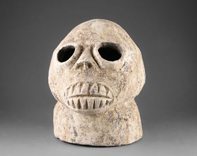 un gros plan d'un masque en pierre sur fond gris