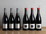 six bouteilles de vin rouge alignées sur une table en bois