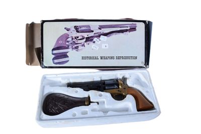 un pistolet dans une boîte sur fond blanc, avec une crosse noire