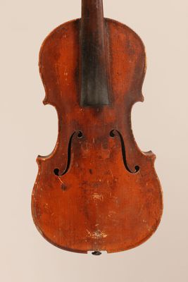 an old violin hanging from a string on a white wall