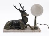 a statue of a stag sitting on a marble base with a lamp on it