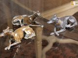 trois figurines de lévriers posées sur une table en verre