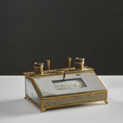 une photo d'un réveil de bureau en or et en verre posé sur une table blanche