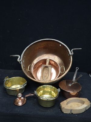 un grand nombre de casseroles et de poêles en cuivre posées sur une table