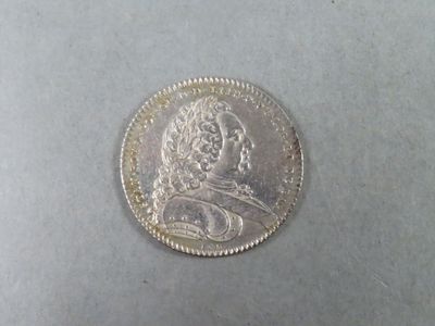 une pièce d'argent sur laquelle figure l'image d'un homme