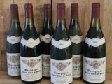six bouteilles de vin sont alignées sur une étagère en bois