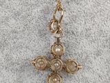 a gold cross pendant with pearls on a gold chain