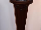 une horloge posée sur un socle dans un coin de la pièce