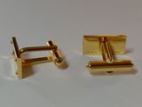 two pairs of gold cufflinks on a white surface