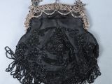 black beaded purse with chain and tassels on a white surface