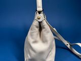 white leather purse with strap on a blue background