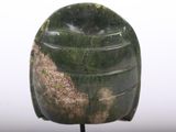a close up of a green stone object on a stand