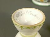 a small white cup with a green rim on a table