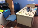 une pièce équipée d'un bureau, de chaises, d'un réfrigérateur et d'un rouleau de papier toilette