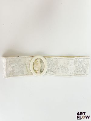 une image représentant une ceinture blanche ornée d'une boucle circulaire